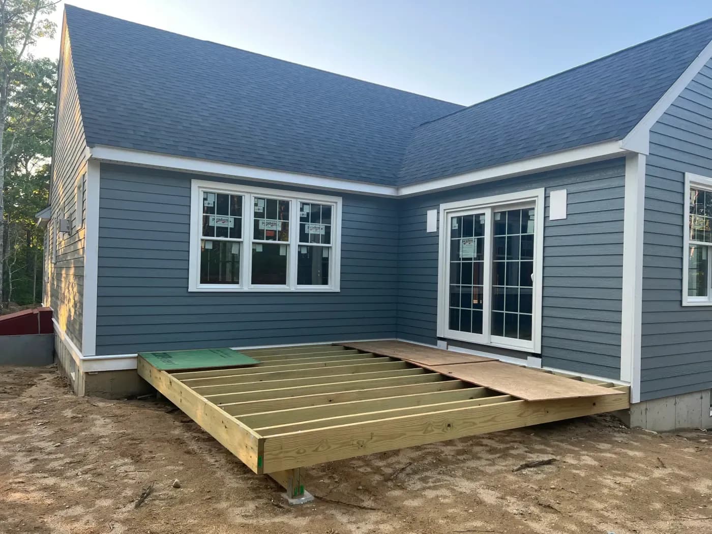Custom deck framing under construction behind a gray-blue sided home